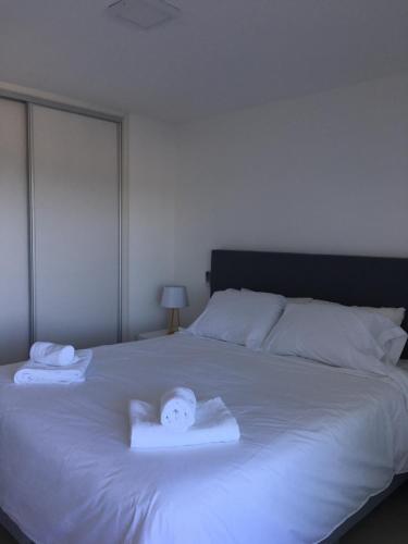 科洛尼亚-德尔萨克拉门托DOS ORILLAS 413 BY GM RENTALS的一张白色的床,上面有两条毛巾