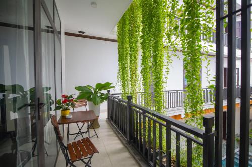 会安Serenity Villa Hoi An的阳台配有桌子和植物