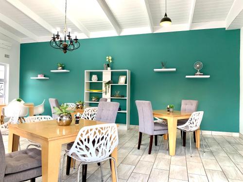 乌姆塔塔Resthaven Guest House的一间拥有蓝色墙壁和桌椅的用餐室