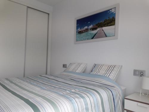 罗尔丹Las Terrazas Golf Resort Rental的白色的卧室配有一张床,墙上挂着一幅画