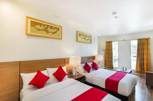 桑托斯将军城OYO 489 Casa Mia Hotel Suites的两张位于酒店客房的床,配有红色和白色枕头