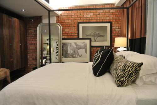 怡保M精品酒店的卧室配有一张白色大床和砖墙