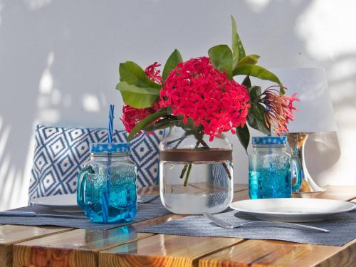 克拉伦代克ChuChubi Studio Apartment Bonaire的一张桌子,上面有花瓶,上面有红花