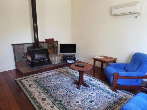 巴林Woodlands of Balingup Bush Cottages的客厅配有蓝色椅子、桌子和壁炉