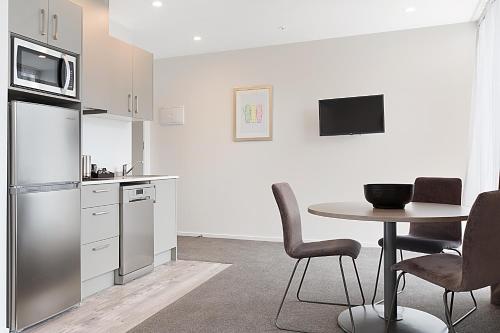 奥克兰Ramada Suites Victoria Street West的厨房配有桌子、冰箱和桌椅