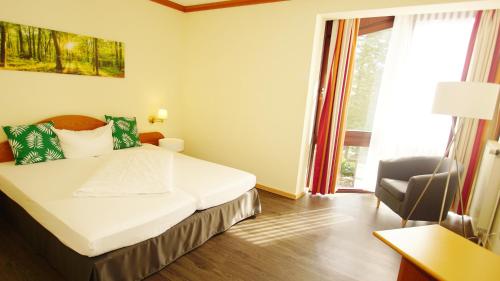 海格尔gut-Hotel Tannenhof的卧室配有床、椅子和窗户。
