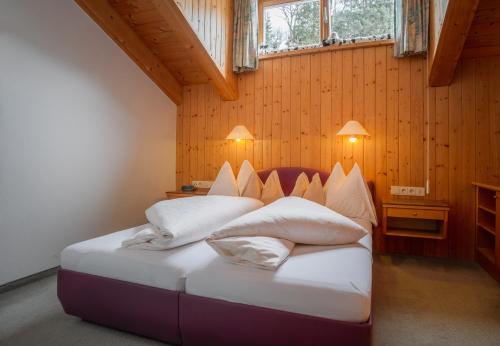 莱赫阿尔贝格朱莉安娜旅馆的一间带两张床铺的卧室,位于带木墙的房间内