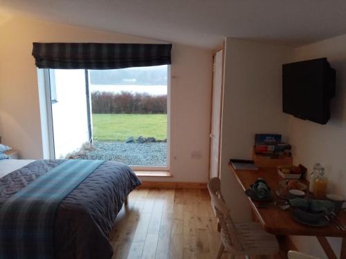 SkeabostKiloran Self Catering Suite的一间卧室配有一张床、一张书桌和一个窗户。