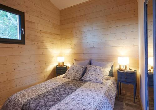 DigosvilleAu courtil des chênes marins, meublé 3 étoiles的卧室配有木墙内的一张床