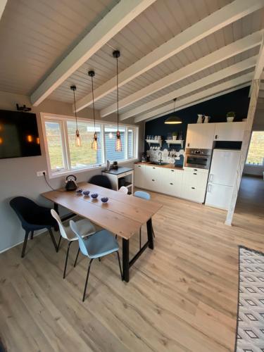 SnæfellsbærNátthagi Luxury Cottage的厨房以及带木桌和椅子的用餐室。