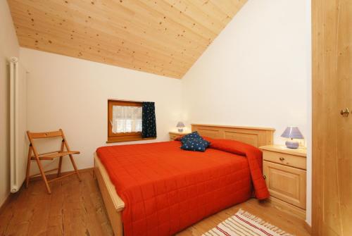 普雷达佐Casa Seler - Appartamento verde的一间卧室配有红色的床和椅子