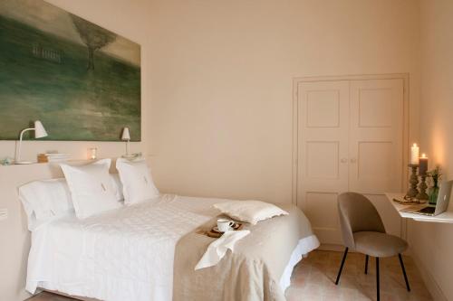 帕尔斯Arkhé Hotel Boutique Pals的卧室配有一张白色的床、一张桌子和一把椅子