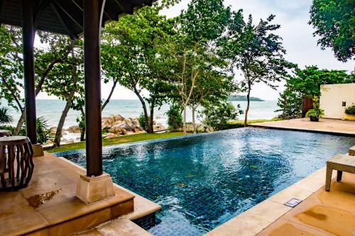 查汶Pawanthorn Samui - SHA Plus的一座位于别墅内的无边游泳池,别墅的背景是大海