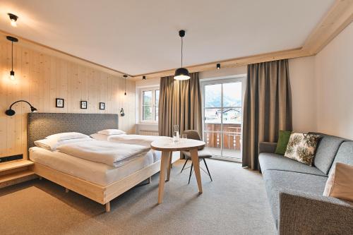 莱赫阿尔贝格Hotel Bianca的一间卧室配有两张床、一张桌子和一张沙发