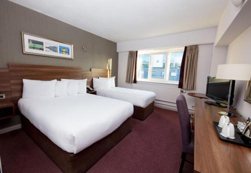 科克Leonardo Hotel Cork的酒店客房配有两张床和一张书桌