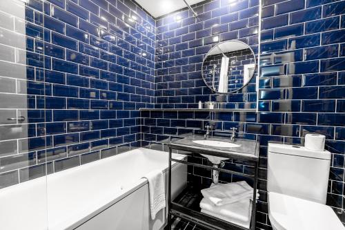 皮布尔斯帕克旅馆的蓝色瓷砖浴室设有浴缸和水槽