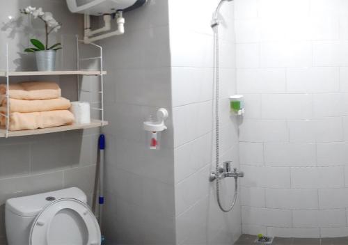 日惹Apartemen Taman Melati Sinduadi 61的浴室设有卫生间和带毛巾的淋浴。