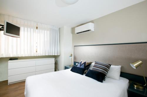 荷兹利亚海洋高地套房公寓式酒店的卧室配有带蓝色枕头的大型白色床