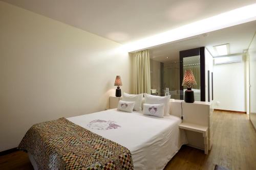 皮尼昂Quinta Rainha Santa Mafalda的一间卧室配有一张带两盏灯的大型白色床。