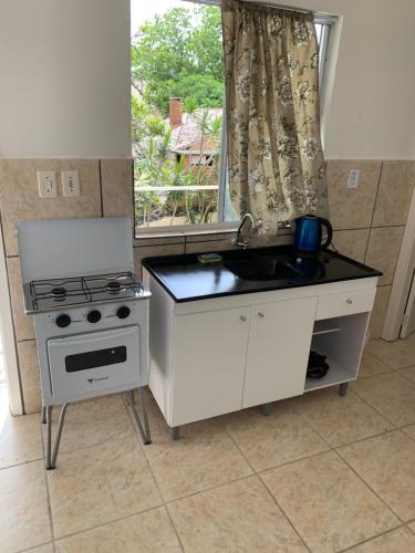 南圣洛伦索Ap beira da Praia das Ondinas的厨房配有水槽、炉灶和窗户。