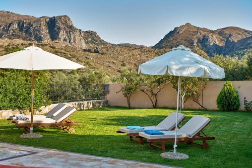 MouríonMouri Villa的两把椅子和遮阳伞,位于带山脉的草坪上
