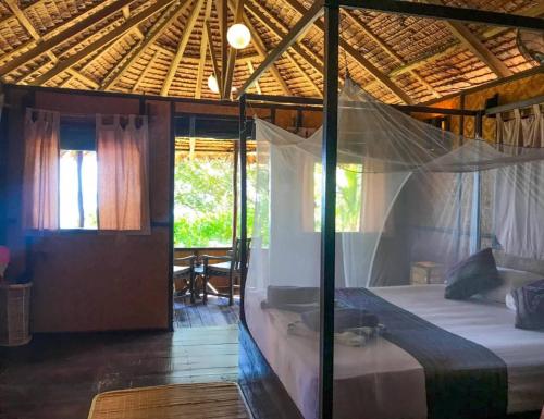 诗巫岛Rimba Resort - Dive Centre & Spa的一间卧室配有一张带蚊帐的床