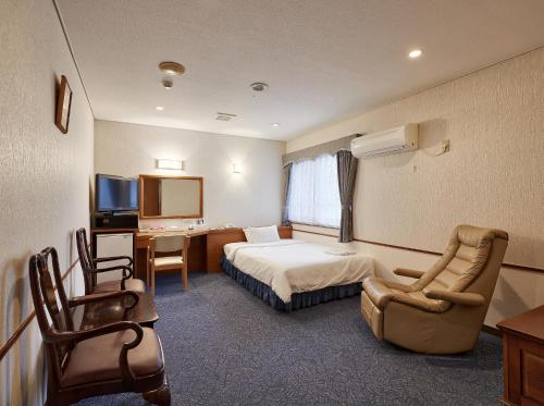 冲绳岛市Crown Hotel Okinawa的酒店客房,配有一张床、一张桌子和椅子