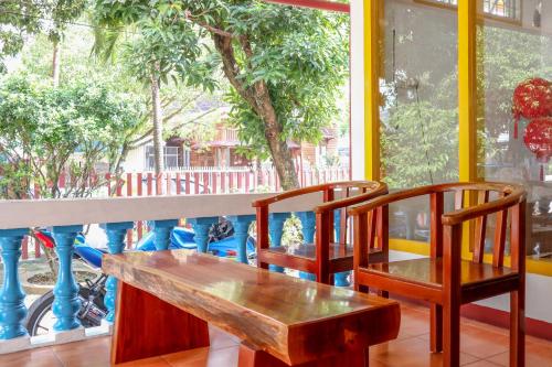巴东Wisma Mutiara的窗前的木凳和两把椅子