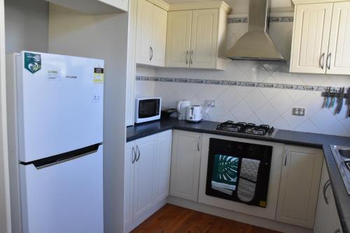 达博Fitzroy haven的厨房配有白色橱柜和白色冰箱。