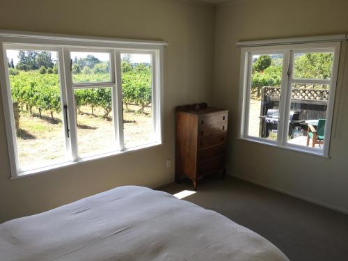 北哈夫洛克Tuki Vineyard Cottage的一间卧室设有2扇窗户、1张床和1张桌子