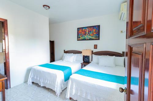 特拉科塔尔潘Hotel Casa Blanca by Rotamundos的一间卧室设有两张床,墙上挂着一幅画