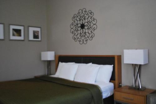 埃尔帕索索鲁纳酒店的一间卧室配有一张带白色枕头的床和两盏灯。