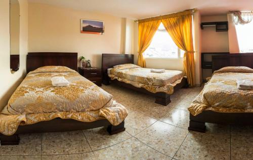 奥塔瓦洛Hostal La Rosa Otavalo的酒店客房设有两张床和窗户。