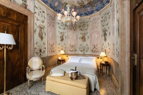 威尼斯Ca' Vendramin Zago的一间卧室配有一张床、一把椅子和一个吊灯。
