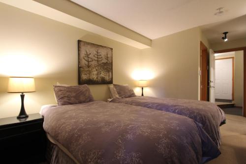 惠斯勒Glacier's Reach by Whistler Retreats的一间卧室配有一张带两盏灯的床。