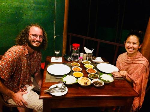 锡吉里亚Chena Huts Eco Resort的坐在餐桌旁吃饭的男人和女人