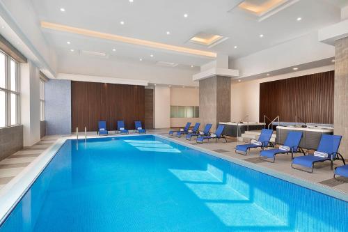 阿可贺巴voco Al Khobar, an IHG Hotel的酒店客房的大型游泳池配有蓝色椅子
