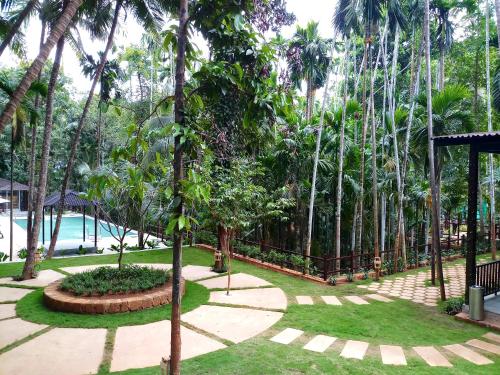 GokarnStone Wood Nature Resort, Gokarna的一座种有棕榈树和游泳池的花园