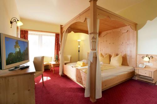 布利克森塔勒Alpenhof Brixen的一间卧室配有一张天蓬床和一台电视机