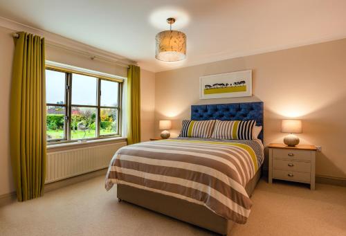 布莱克尼Bramble Lodge的一间卧室配有一张带蓝色床头板的床和窗户