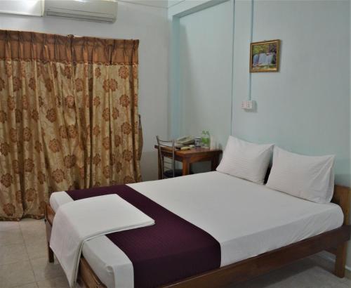 贾夫纳Gnaanams Hotel and Restaurant的一间卧室配有床和窗帘