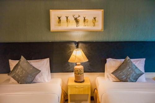 卡伦海滩普若安达曼广场酒店的酒店客房设有两张床和一张桌子上的台灯。