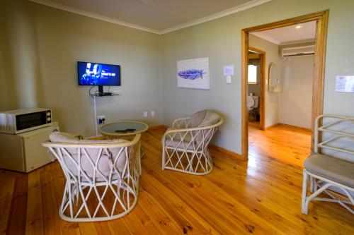 布隆方丹Sangiro Game Lodge的客厅配有两把椅子和墙上的电视