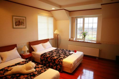 弘前市农庄假日酒店的酒店客房设有两张床,床上有泰迪熊