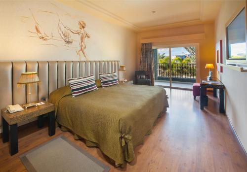 梅罗那瑞斯Lopesan Villa del Conde Resort & Thalasso的一间带大床的卧室和一个阳台
