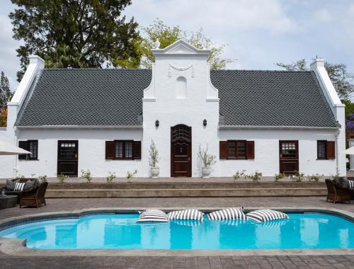 阿多Stellenhof Guest House的一座白色的房子,前面设有一个游泳池