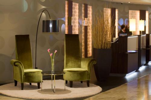 柏林Crowne Plaza Berlin City Centre Ku'damm, an IHG Hotel的大堂设有两把椅子和一张带花瓶的桌子