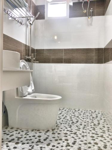 大叻晃武旅馆的浴室铺有黑白地板,设有白色卫生间。