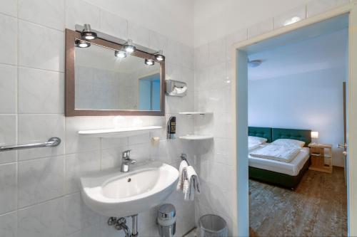 莱茵河畔的宾根克朗酒店的一间带水槽和镜子的浴室以及一张床