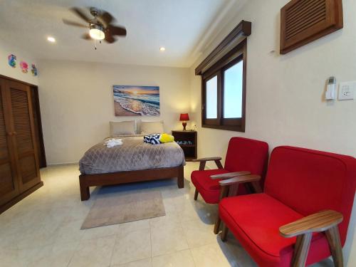 女人岛Coralito Malecon Luxury Studio的一间卧室配有一张床和一张红色椅子